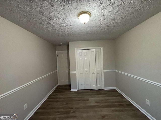 unfurnished room with dark hardwood / wood-style flooring and a textured ceiling