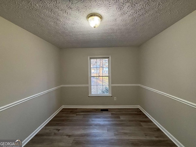 unfurnished bedroom with a closet, dark hardwood / wood-style flooring, multiple windows, and a textured ceiling