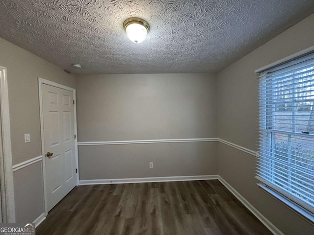 spare room with dark wood-type flooring and a textured ceiling