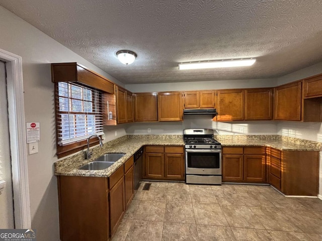 kitchen with a textured ceiling, stainless steel gas range, and light stone counters