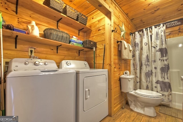 washroom with wood ceiling, washer and clothes dryer, light wood-type flooring, and wood walls