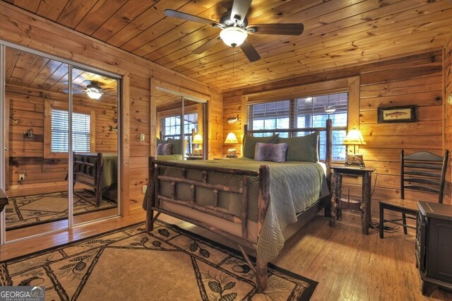 bedroom with multiple windows, light hardwood / wood-style floors, wood ceiling, and wood walls