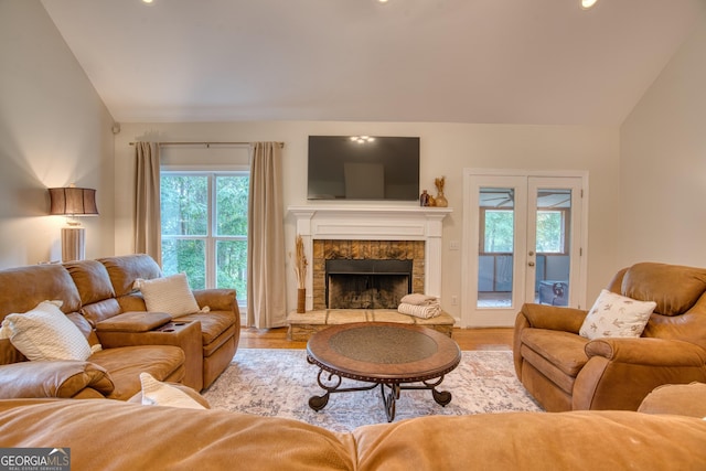 living room featuring french doors, a fireplace, vaulted ceiling, and light hardwood / wood-style flooring