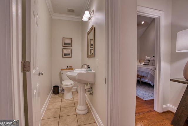 bathroom with tile patterned flooring, crown molding, and toilet