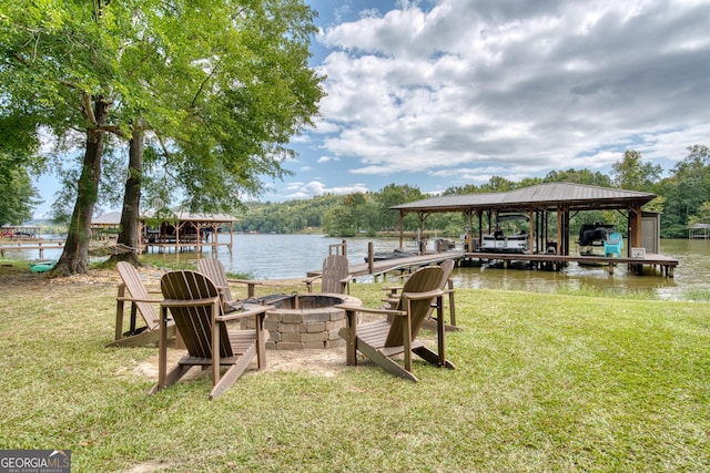 view of dock featuring a water view, an outdoor fire pit, and a yard