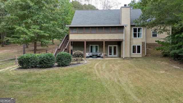 rear view of house featuring a patio, a sunroom, a yard, and french doors