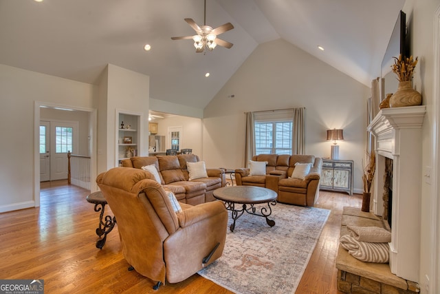 living room with ceiling fan, high vaulted ceiling, light hardwood / wood-style flooring, and built in features