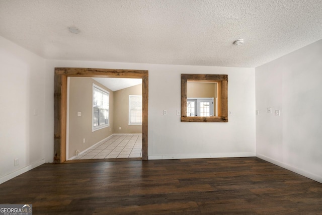 empty room with lofted ceiling, a textured ceiling, and dark hardwood / wood-style flooring