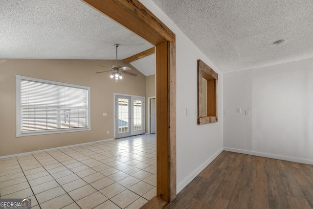 tiled empty room with french doors, ceiling fan, a textured ceiling, and vaulted ceiling with beams