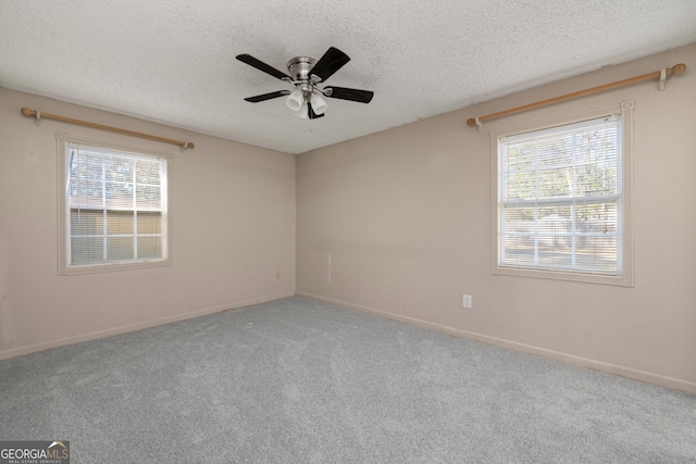 carpeted spare room featuring ceiling fan, plenty of natural light, and a textured ceiling