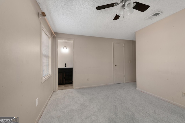 unfurnished room with ceiling fan, light colored carpet, and a textured ceiling