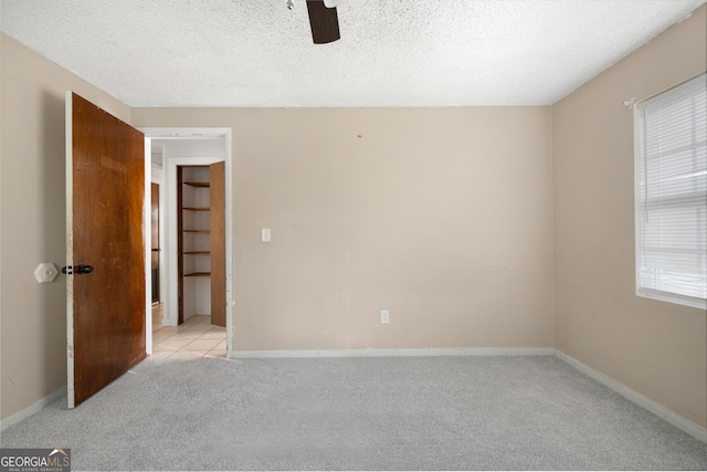 carpeted spare room featuring ceiling fan and a textured ceiling