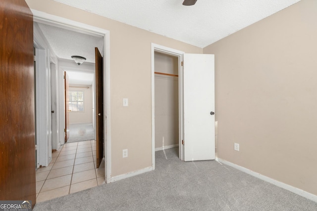 unfurnished bedroom with light carpet, a closet, and a textured ceiling