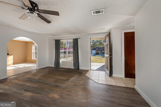 empty room with hardwood / wood-style flooring, plenty of natural light, and a textured ceiling