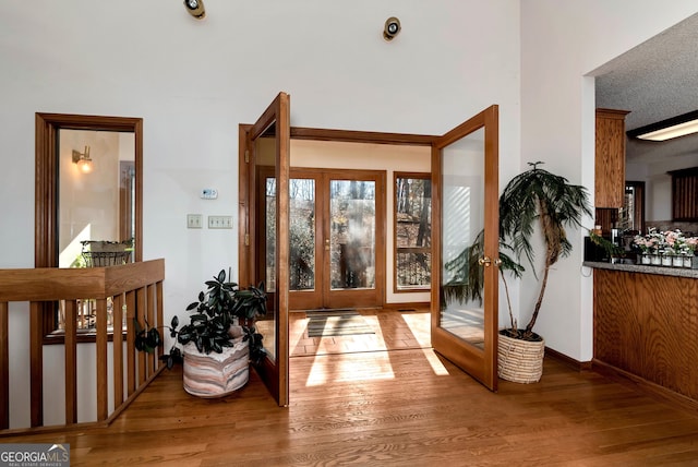 foyer entrance with french doors, wood-type flooring, and a textured ceiling