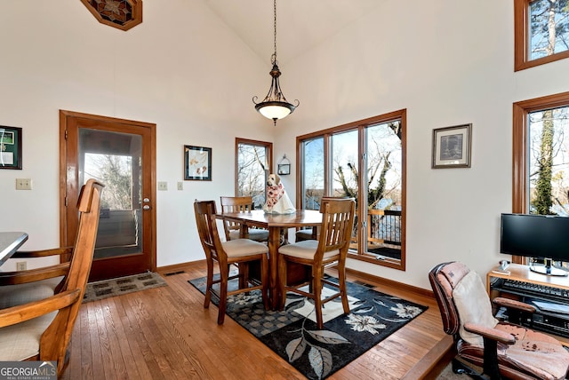 dining space featuring hardwood / wood-style flooring and high vaulted ceiling