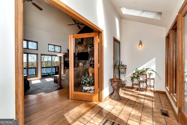 corridor featuring high vaulted ceiling, a textured ceiling, and light wood-type flooring