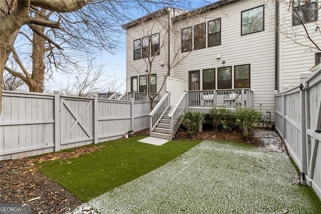 back of property featuring a wooden deck and a yard