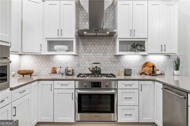 kitchen featuring stainless steel appliances, white cabinets, backsplash, and wall chimney exhaust hood