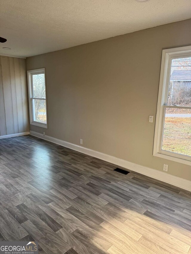 empty room with dark hardwood / wood-style floors and a textured ceiling