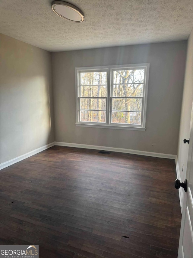 spare room featuring dark hardwood / wood-style floors and a textured ceiling