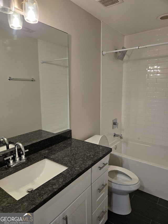 full bathroom featuring vanity, tiled shower / bath combo, and toilet