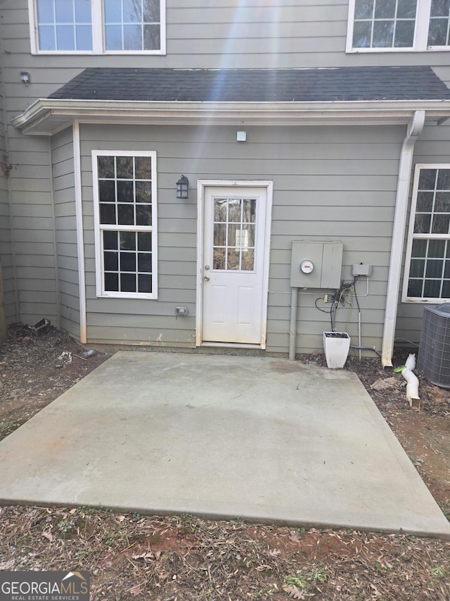 view of exterior entry with central AC unit and a patio area