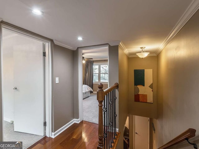 corridor with wood finished floors, an upstairs landing, baseboards, and ornamental molding