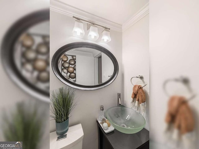 half bathroom featuring toilet, vanity, and crown molding