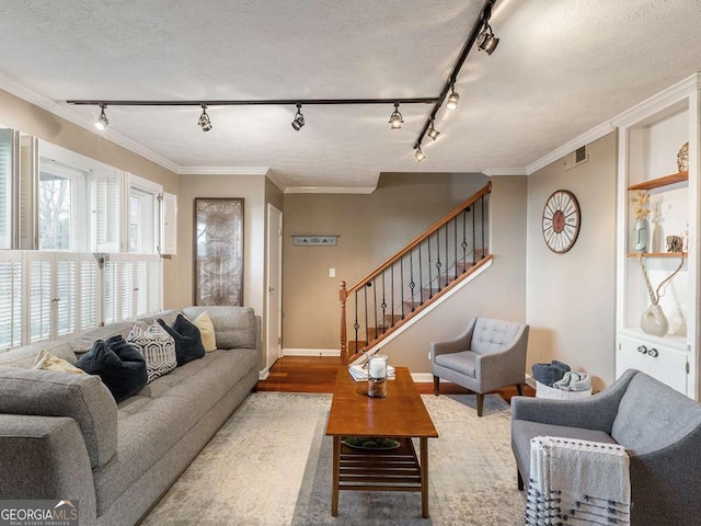 living room featuring hardwood / wood-style flooring, ornamental molding, and a textured ceiling