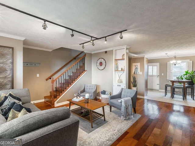 living area featuring visible vents, a textured ceiling, wood finished floors, crown molding, and stairs