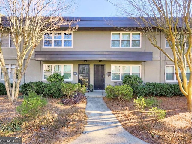 townhome / multi-family property featuring solar panels, covered porch, and stucco siding