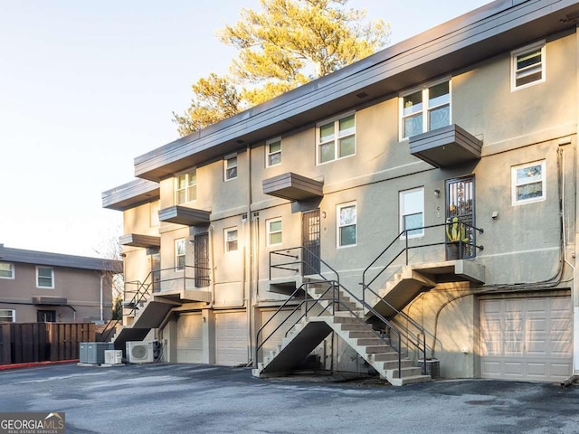 exterior space with stucco siding, a garage, central AC, and stairs