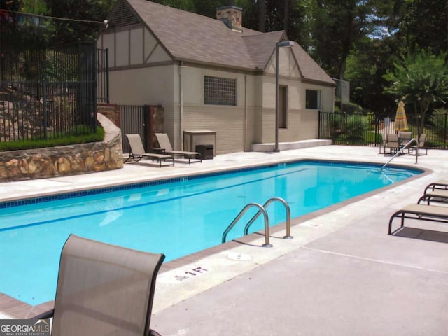 community pool featuring a patio, an outdoor structure, and fence