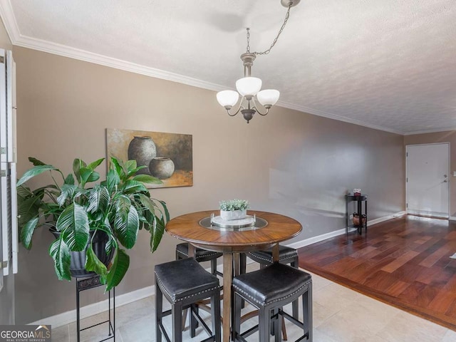 dining space featuring baseboards, an inviting chandelier, ornamental molding, and light wood finished floors