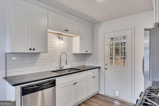 kitchen featuring appliances with stainless steel finishes, sink, white cabinets, and light wood-type flooring