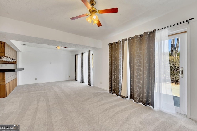 carpeted living room featuring bar area and ceiling fan