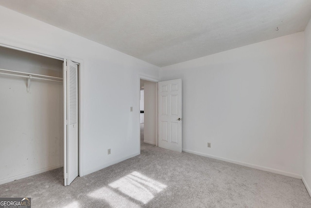 unfurnished bedroom featuring light carpet, a closet, and a textured ceiling