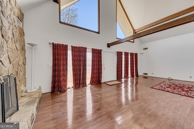 living room with high vaulted ceiling, plenty of natural light, a fireplace, and hardwood / wood-style floors