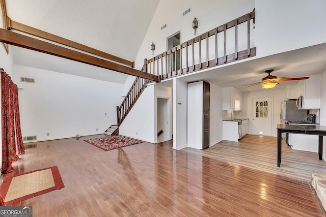 living room featuring sink, high vaulted ceiling, ceiling fan, and light wood-type flooring