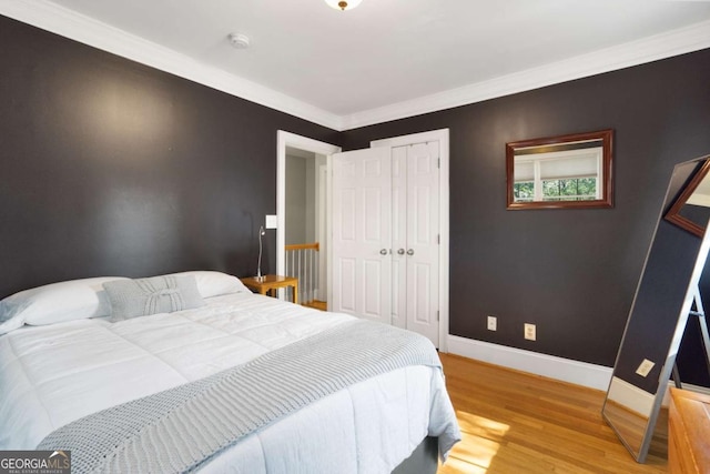 bedroom with hardwood / wood-style flooring, crown molding, and a closet