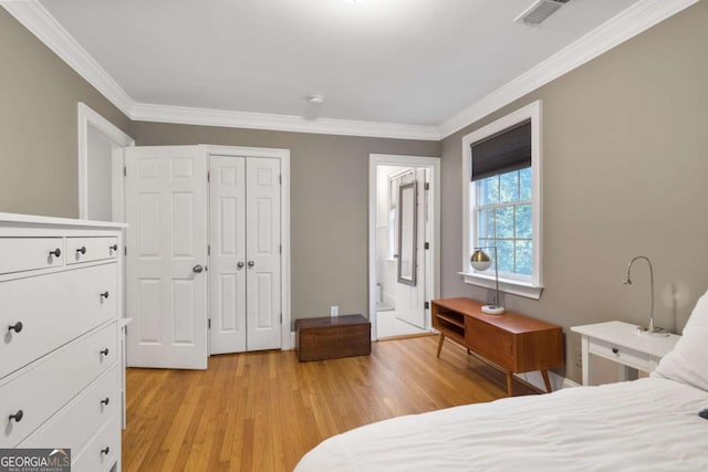 bedroom featuring crown molding, ensuite bath, a closet, and light hardwood / wood-style flooring