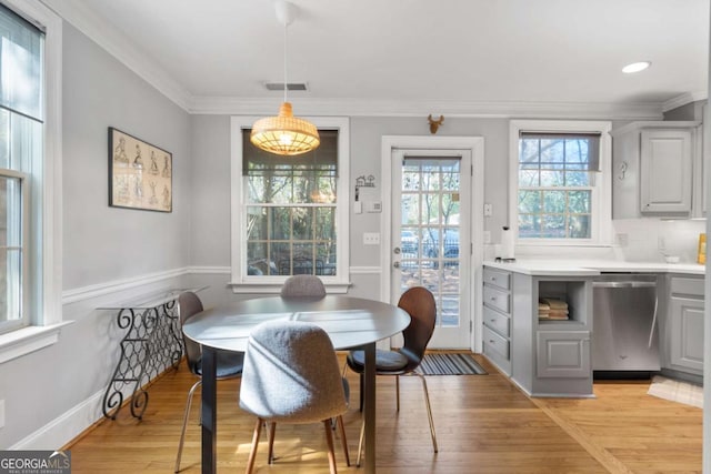 dining space with crown molding and light hardwood / wood-style flooring