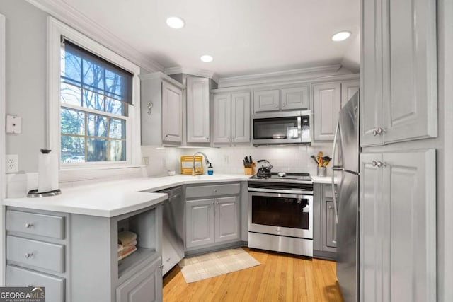 kitchen featuring tasteful backsplash, appliances with stainless steel finishes, and gray cabinetry