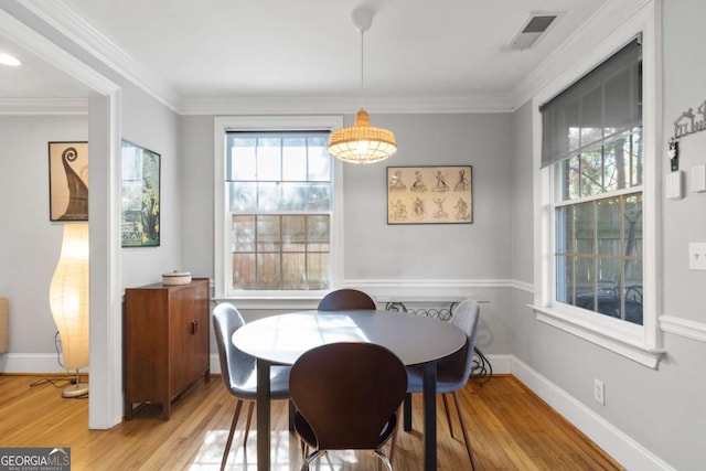 dining area with ornamental molding and light hardwood / wood-style floors