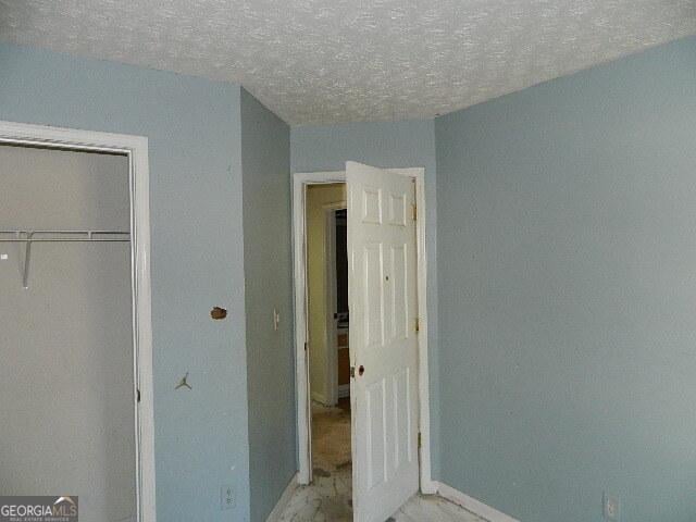 unfurnished bedroom featuring a textured ceiling and a closet