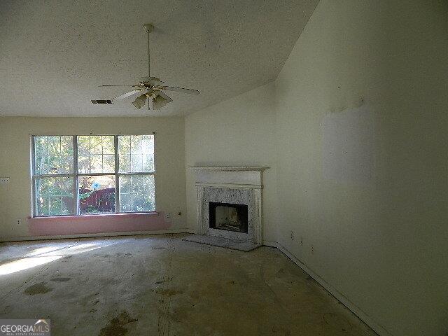 unfurnished living room featuring ceiling fan, vaulted ceiling, and a fireplace