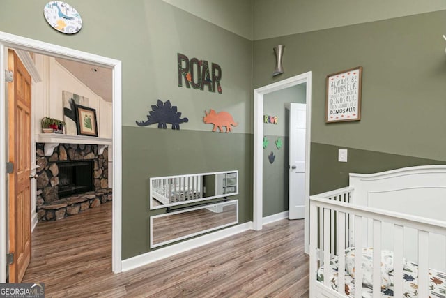 bedroom featuring hardwood / wood-style floors, a fireplace, and a nursery area