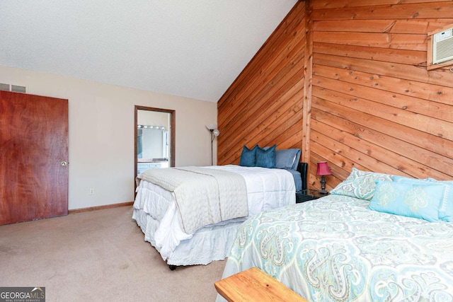 carpeted bedroom with vaulted ceiling, ensuite bath, a textured ceiling, and wood walls