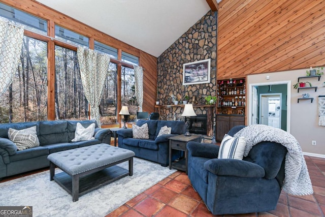 living room featuring wooden walls, a fireplace, and high vaulted ceiling